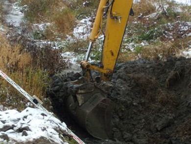 An excavator digs a trench in the ground