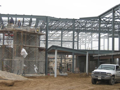 Workers construct a brick exterior wall along the newly installed metal girder frame, which will become the new Regional Recreation Complex