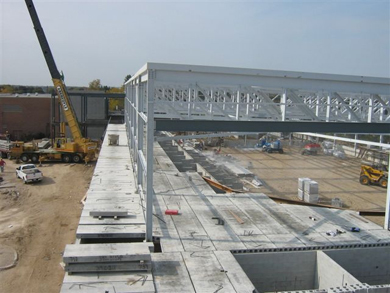 The cement walls, metal roof girders and supports are installed using a crane and other construction vehicles