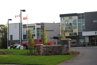 Amid a landscaped entranceway and freshly paved parking lot, now stands the new Regional Recreation Complex, with gray concrete exterior walls and yellow paneled windows