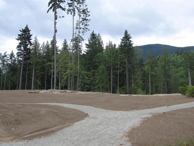 A new gravel pathway leading through open areas of landscaped topsoil, ready for seeding