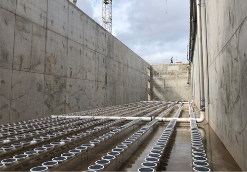 An empty water treatment tank with a crane in the background.