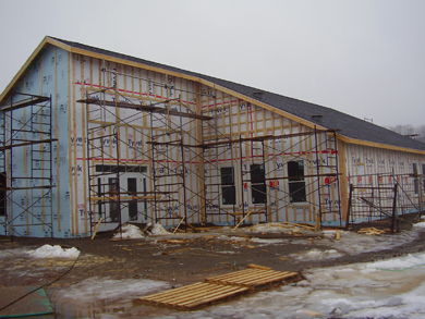 Installing foam insulation to the exterior walls of the building and finalizing the shingled roof