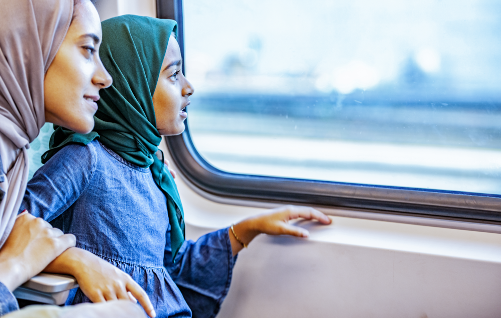 Mother and daughter sitting on a train, looking out the window