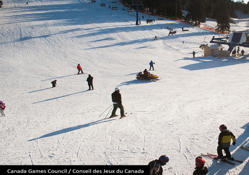 A snowy ski hill with a chairlift, skiers, and a snowboarder