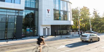 A person cycling in front of the John W. Lindsay YMCA building.