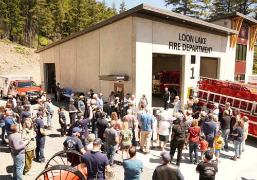 A gathering of people in front of a firehall.