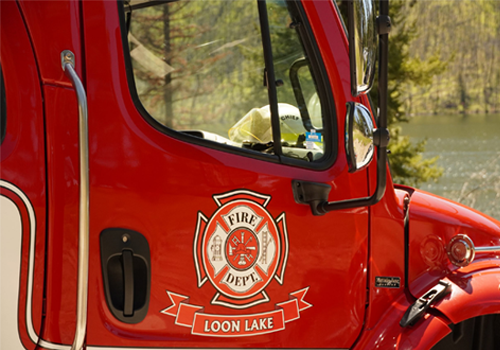 A close-up of the passenger door of a firetruck with an emblem featuring firefighting tools.