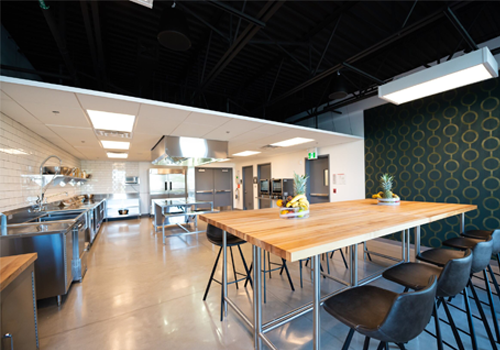 Industrial style kitchen with stainless steel appliances and a seating area.