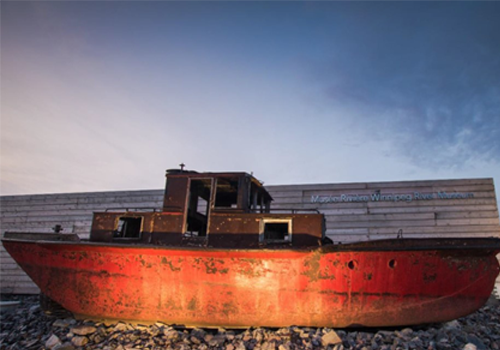 An old rusty ferry in front of a wooden fence.