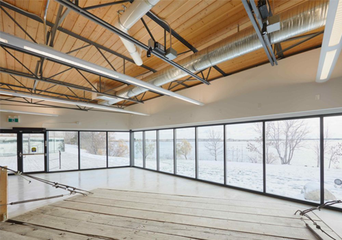 Interior of a modern space with large windows and wooden floors.