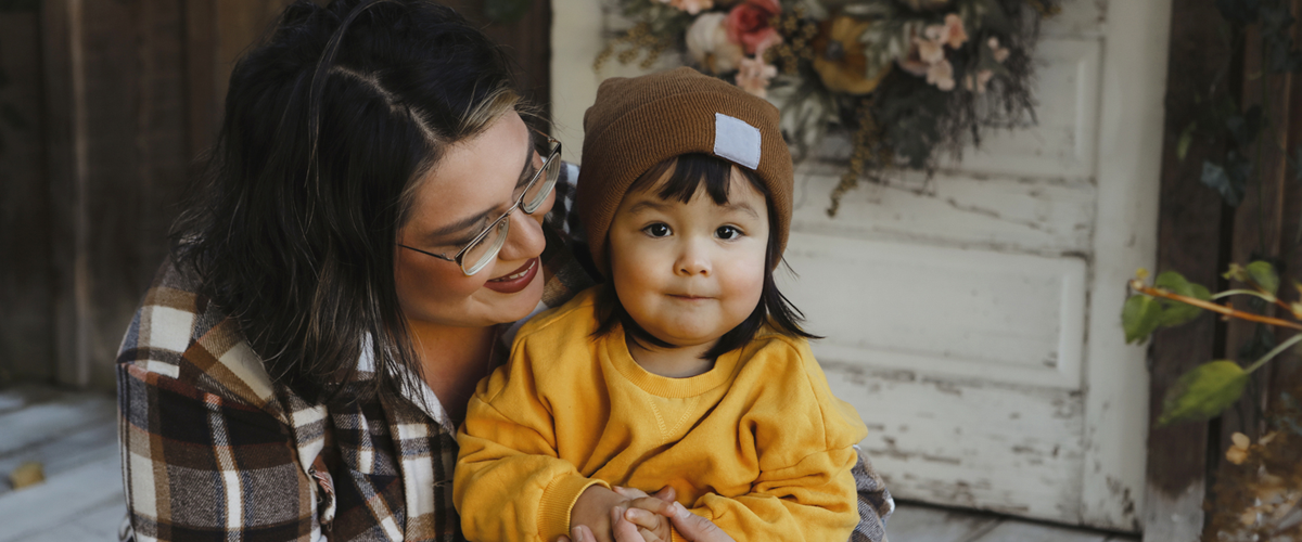 A parent sits on the porch while embracing their child.