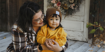 A parent sits on the porch while embracing their child.